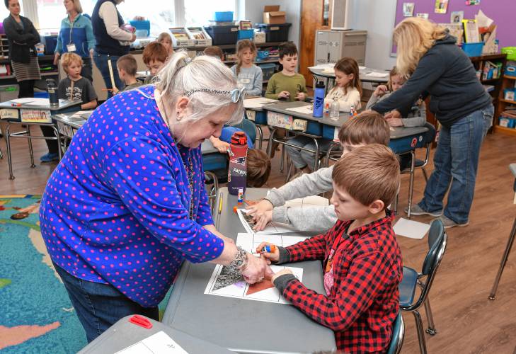 Suzanne Balcanoff of Greenfield helps second grade students at Conway Grammar School make quilt squares during Math Day on Tuesday. Activities throughout the school were aimed at recognizing the relationship between math, art and music.