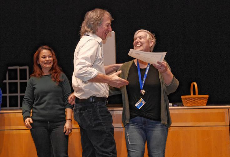 Turners Falls High School history teacher David Smith, center, receives the McGraw Uplift Award from teacher Jessica Vachula-Curtis during an assembly at the school Friday morning. At left is teacher Heidi Schmidt.