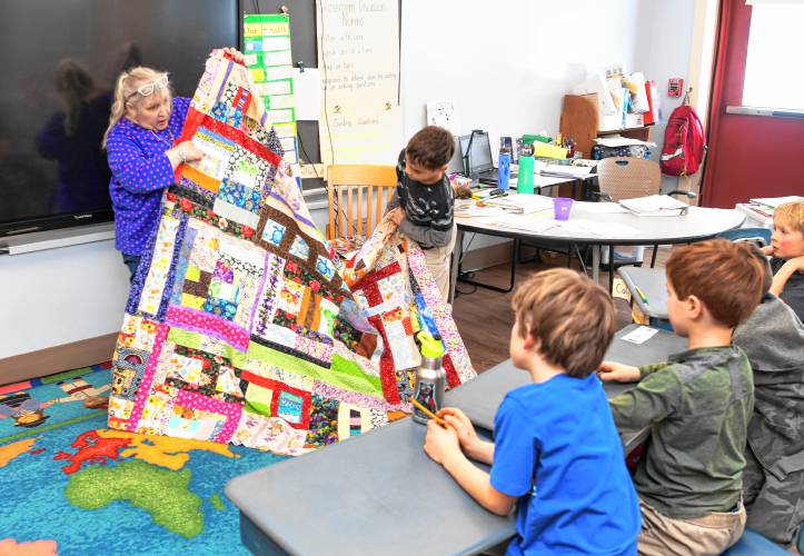 Suzanne Balcanoff of Greenfield holds up a puzzle quilt demonstrating the correlation between math and art to second grade students during Conway Grammar School’s Math Day on Tuesday. Activities throughout the school were aimed at recognizing the relationship between math, art and music.