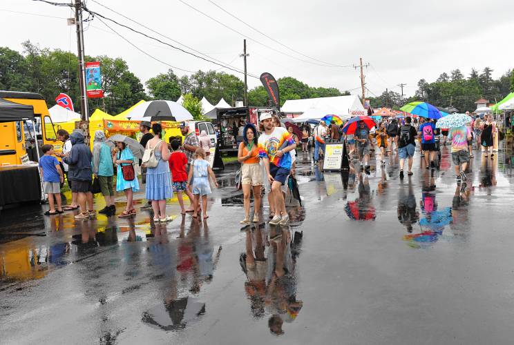 People walk past rows of food vendors at the Green River Festival on Friday night at the Franklin County Fairgrounds after a slight rain delay.