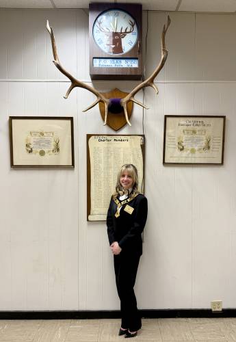 Montague Elks Lodge #2521 Exalted Ruler Allie Cooke in front of the Montague Elks charter that was created in 1974. She was installed on March 22 as the youngest female exalted ruler the lodge has seen in its 50 years of existence.