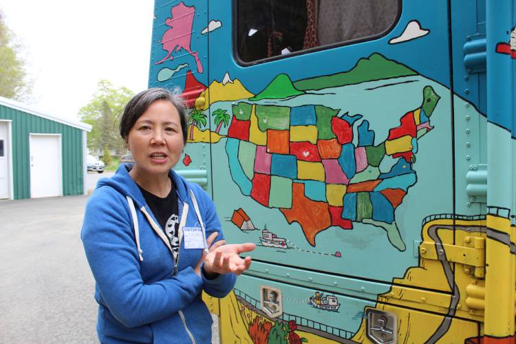 Children’s book illustrator Robbi Behr in front of the map she painted on a converted school bus that showcases the different locations across the country that the Busload of Books has visited.