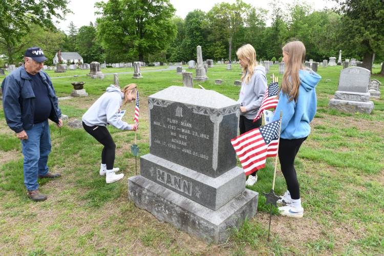 Veteran Lawrence Ashman of Whately and members of Frontier Regional School’s National Honor Society chapter Ashlie Galenski, Addison Morrey and Macy DeMaio place flags at Brookside Cemetery in South Deerfield on Wednesday morning.