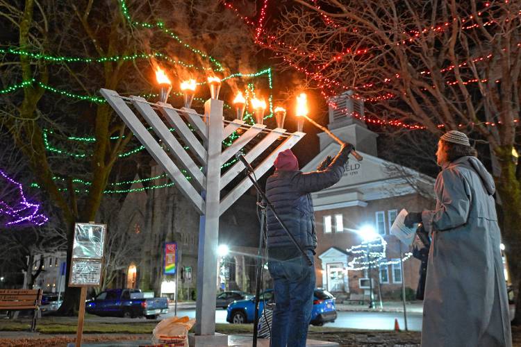 Greenfield Board of Assessors Chair Jim Geisman lights the menorah on the Greenfield Common with Jasper Lapienski on the sixth day of Hanukkah on Monday.