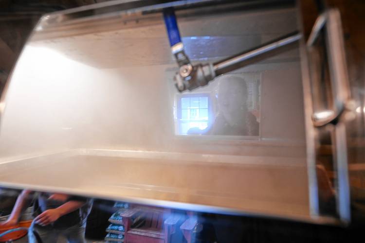 A student from Bernardston Elementary School’s fifth grade class looks though the steam rising off of Jordan DiGeorge’s evaporator at Bald Mountain Sugar House in Bernardston on Friday.