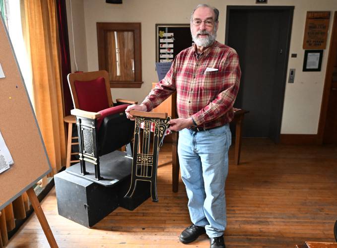 Jim Kessler, president of the Memorial Hall Association, with a sample of the replacement chairs for the theater in Memorial Hall in Shelburne Falls.