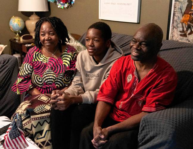 Asani Furaha, left, and Mateso Kagenyekero, right, sit with their son, Divin Mwami Heri at their home in Northampton. The family, which arrived from the Democratic Republic of the Congo in 2018, credited Catholic Charities and the Center for New Americans for helping them gain citizenship, but said they still worry they could be targeted.