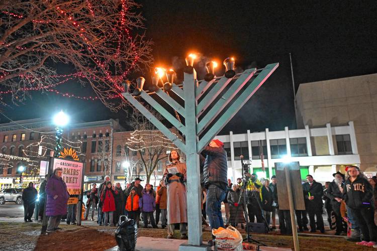 Greenfield Board of Assessors Chair Jim Geisman lights the menorah on the Greenfield Common with Jasper Lapienski on the sixth day of Hanukkah on Monday.
