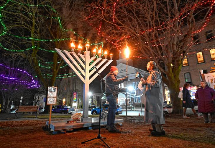Greenfield Board of Assessors Chair Jim Geisman lights the menorah on the Greenfield Common with Jasper Lapienski on the sixth day of Hanukkah on Monday.
