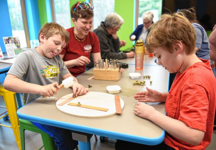 Erving resident Dalton Towne, 8, left, hammers a pattern into a leather strip as Cate Avery-Jagla and her son Abraham Jagla, 10, also of Erving, pick out their next dye as they tool leather at a workshop sponsored by the Erving Public Library and LaunchSpace on Wednesday at the library. Erving resident Dalton Towne, 8, left, hammers a pattern into a leather strip as Cate Avery-Jagla and her son Abraham Jagla, 10, also of Erving, pick out their next dye as they tool leather at a workshop sponsored by the Erving Public Library and LaunchSpace on Wednesday at the library.