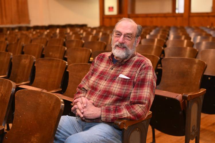 Jim Kessler, president of the Memorial Hall Association, with the old seats in the theater at Memorial Hall in Shelburne Falls.