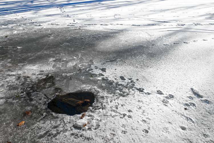 A hole shows the Mill River running beneath the ice in Northampton.
