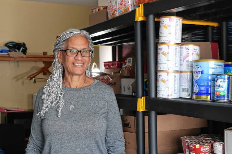 Marisa Perez poses for a photo in a small pantry of donated goods at the Days Inn, where clients of the emergency shelter can get snacks or microwavable meals.