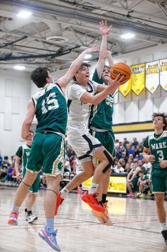 Pioneer’s Kurt Redeker (3) drives to the hoop between Ware defenders Jack Gaudreau (15) and Justin Grout (25) in the second quarter of the MIAA Division 5 quarterfinal Friday night in Northfield.