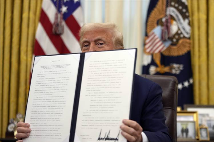 President Donald Trump signs an executive order in the Oval Office of the White House on Jan. 23.