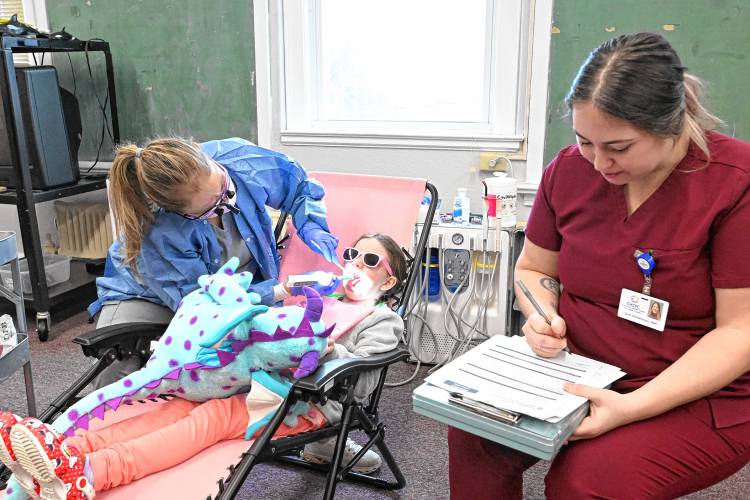 Dental hygienist Jennifer Hauschild of J&S Smile Pros and Community Health Center of Franklin County dental hygienist Sarie Whitehouse screen children at the Head Start program in Turners Falls on Wednesday.