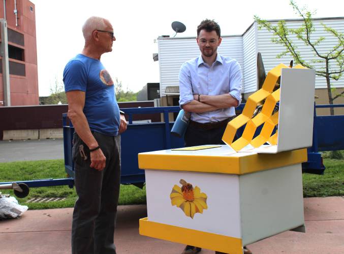 Artist Thor Holbek, at left, stands in front of the beehive sculpture on Bank Row in Greenfield that he restored after it was vandalized. At right is Greenfield’s Economic and Community Development Assistant Christian LaPlante.