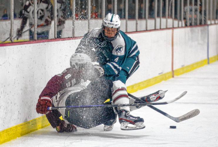 Greenfield’s Shawn Baumann (8) knocks Amherst’s Brach Applegate (4) into the boards earlier this season at Orr Rink in Amherst.