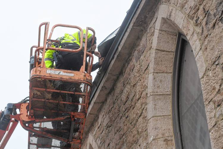 Workers access the damage to the roof of the Episcopal Church of Saints James and Andrew in Greenfield on Wednesday that sustained damage amid high winds.