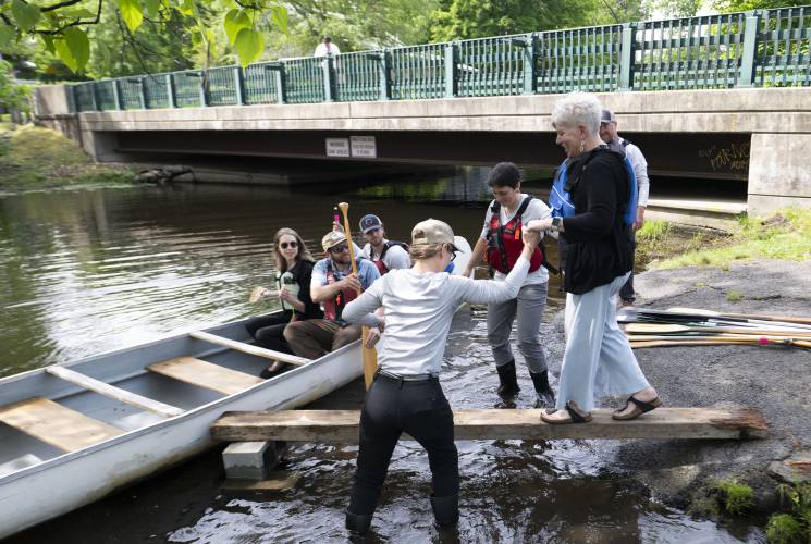 Amy Aubin, director of education at Adventure East, helps Kristin Cole, vice president of workforce development at Greenfield Community College, get  into a canoe on Lake Warner in North Hadley. The group was there with Lauren Jones, secretary of the state’s Executive Office of Labor and Workforce Development. 