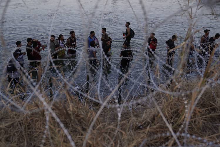 Migrants wait to climb over concertina wire after they crossed the Rio Grande and entered the U.S. from Mexico, Sept. 23, 2023, in Eagle Pass, Texas. Migrants wait to climb over concertina wire after they crossed the Rio Grande and entered the U.S. from Mexico, Sept. 23, 2023, in Eagle Pass, Texas.