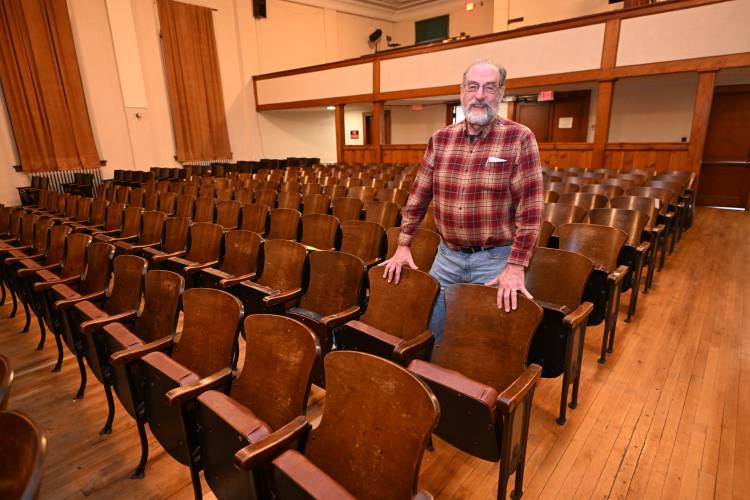 Jim Kessler, president of the Memorial Hall Association, with the old seats in the theater at Memorial Hall in Shelburne Falls.