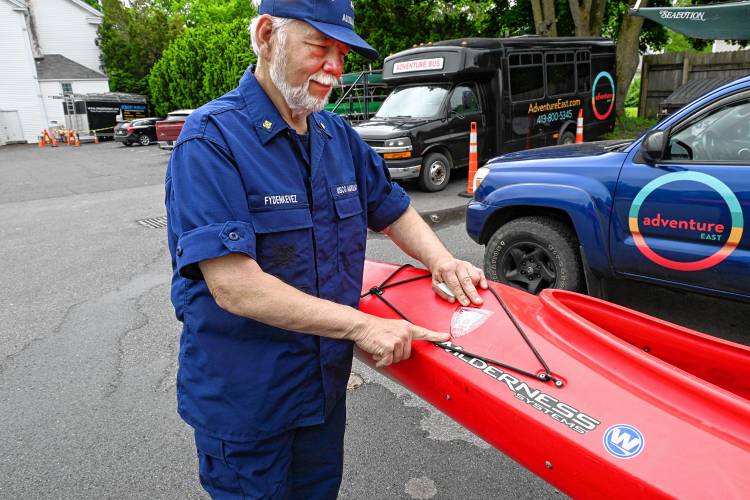 Tom Fydenkevez of the U.S. Coast Guard Auxiliary puts a vessel safety check sticker on a tandem kayak at Adventure East in Sunderland on Monday. 