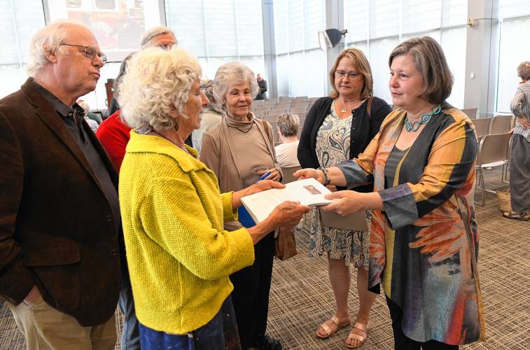 Wendell resident Nina Keller along with other members of the citizens group No Assault & Batteries, hands state Sen. Jo Comerford, right, a petition with at least 500 signatures against the battery energy storage system proposed for Wendell at Comerford’s People’s Town Hall at Greenfield Community College on Monday.