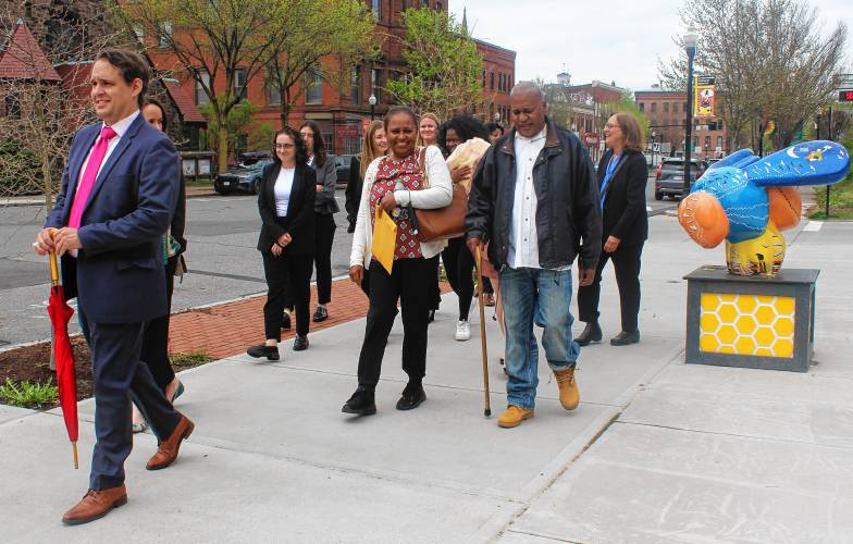 STAFF PHOTO/DOMENIC POLI Led by his attorney, Ira Gant, far left, Elvio J. Marrero, with cane, walks near the Greenfield Public Library with his sister and members of the Boston College Innocence Program to test out his GPS monitoring device on Tuesday after posting $5,000 bail in Franklin County Superior Court. He has been in prison for a 1994 murder but the state Supreme Judicial Court on Jan. 11 ordered a new trial.