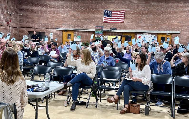 Voters raise their “yes” cards during Annual Town Meeting on Tuesday in Shelburne.