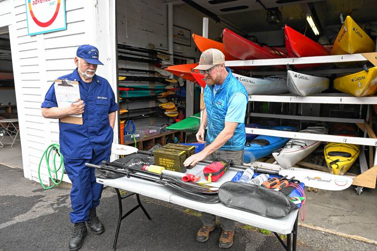 Tom Fydenkevez of the U.S. Coast Guard Auxiliary checks out safety equipment Brian Pearson at Adventure East uses on his water trips. 