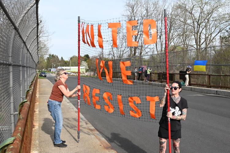 Kelly Feeney and Mira Ishii of Amherst hold a sign on the Mountain Road Bridge over Interstate 91 in Hatfield, just south of the Whately town line, on Tuesday afternoon.