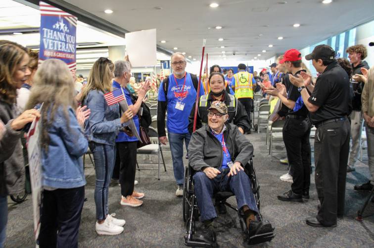 Montague resident Lee Evers, 102, a World War II veteran, is cheered on as his grandson Arieh Kurinsky helps push him down the line of people to begin boarding a flight to Washington D.C. through Honor Flight Connecticut on May 3.