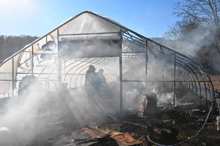 People use hoses to help extinguish a greenhouse fire on Jones Road in Deerfield on Tuesday afternoon. 