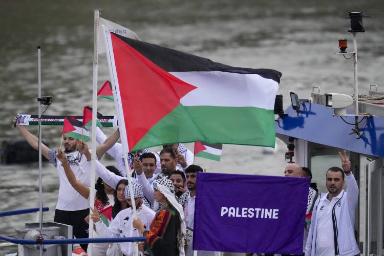 Palestinian flag bearers Wasim Abusal and Valerie Rose Tarazi travel with teammates along the Seine River in Paris, France, during the opening ceremony of the 2024 Summer Olympics, Friday, July 26, 2024. (AP Photo/Kirsty Wigglesworth)