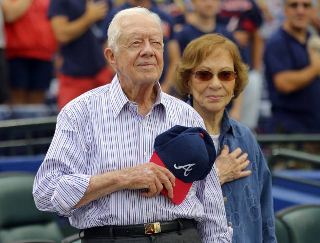 FILE - Former President Jimmy Carter and his wife, Rosalynn, stand for the national anthem before a baseball game between the Atlanta Braves and the San Diego Padres, June 10, 2015, in Atlanta.