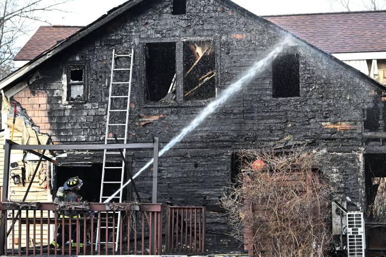 Firefighters look for hot spots at a two-alarm fire at 41 Rogers Ave. in Orange on Sunday afternoon.