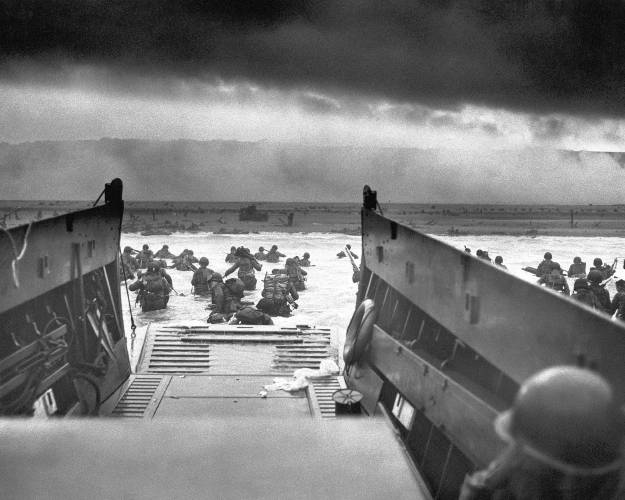 This photograph is believed to show E Company, 16th Regiment, 1st Infantry Division, participating in the first wave of assaults during D-Day in Normandy, France, June 6, 1944. The greatest armada ever assembled, nearly 7,000 ships and boats, supported by more than 11,000 planes, carried almost 133,000 troops across the Channel to establish toeholds on five heavily defended beaches stretched across 80 kilometers (50 miles) of Normandy coast. More than 9,000 Allied soldiers were killed or wounded in the first 24 hours.