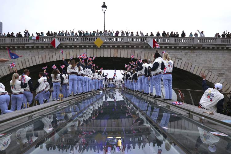 Spectators cheer as Great Britain athletes pass under a bridge along the Seine River during the opening ceremony for the 2024 Summer Olympics in Paris, France, Friday, July 26, 2024. (Naomi Baker/Pool Photo via AP)