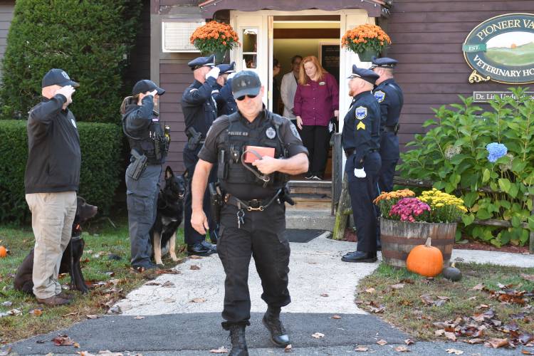 Montague Police Officer James Ruddock walks out of the Pioneer Valley Veterinary Hospital in Greenfield on Tuesday with the cremated remains and collar of his K-9, Artie, who was euthanized on Oct. 2. He is walking between an honor guard of fellow K-9s and local police.