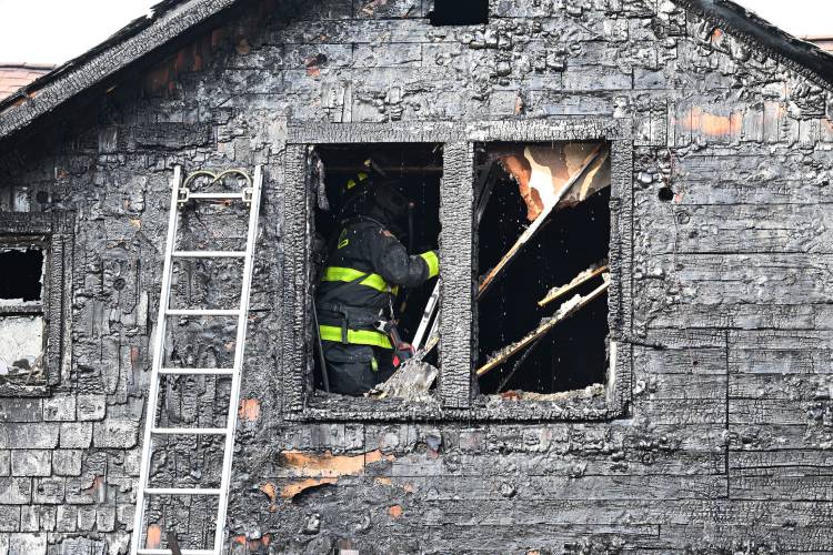 Firefighters look for hot spots at a two-alarm fire at 41 Rogers Ave. in Orange on Sunday afternoon.