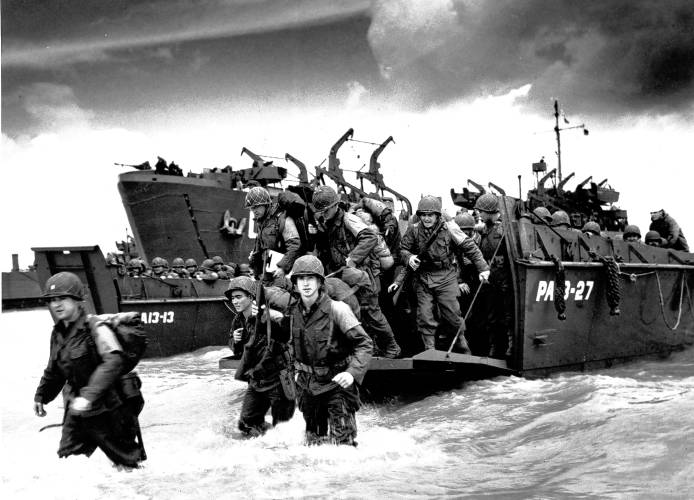 American reinforcements, arrive on the beaches of Normandy from a Coast Guard landing barge into the surf on the French coast on June 23, 1944 during World War II. They will reinforce fighting units that secured the Norman beachhead and spread north toward Cherbourg.