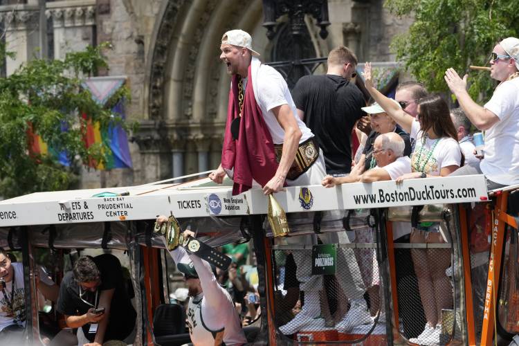 Boston Celtics' Kristaps Porzingis celebrates with fans during team's NBA basketball championship duck boat parade Friday, June 21, 2024, in Boston. (AP Photo/Michael Dwyer)