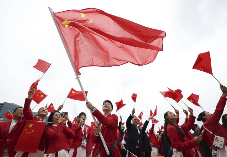 China's Olympic athletes wave national flags from a boat for the opening ceremony of the 2024 Summer Olympics on the Seine River in Paris, Friday, July 26, 2024. (Cao Can/Pool Photo via AP)
