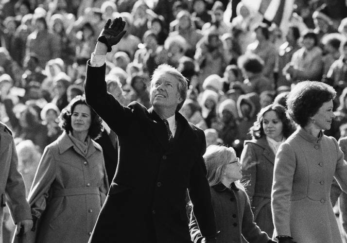 President Jimmy Carter waves to the crowd while walking with his wife Rosalynn and their daughter Amy along Pennsylvania Avenue from the Capitol to the White House following his inauguration, Jan. 20, 1977, in Washington.