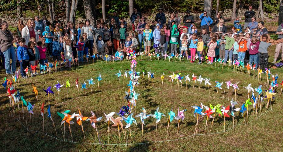Students, faculty and visitors gather around a peace sign filled in with pinwheels made by students at Leverett Elementary School as a way to celebrate International Peace Day on Tuesday.