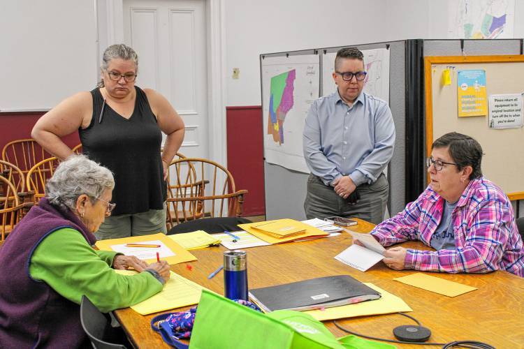 Poll workers Peg Saulnier, at left, and Cathy Marcum, at right, work to tabulate the 10 mail-in ballots that were received on or after Election Day on Nov. 5. City Clerk Kathy Scott and Assistant City Clerk Quinn Jaquins, standing, help oversee the process at Greenfield City Hall on Tuesday.
