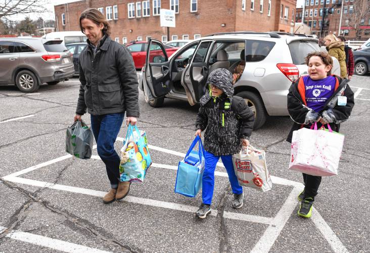 United Way of the Franklin & Hampshire Region Executive Director Geoff Naunheim carries donations for the 20th annual Supper for Six food drive with volunteers James Bresciano, 9, and Gabriel Heineman, 10, both of Greenfield, to the Davis Street offices in Greenfield on Thursday. Thanks to those who contributed, 403 local families will receive help putting food on the dinner table over February school vacation week. This includes 350 bags collected, plus $2,666 in monetary donations that will feed another 53 families. United Way partner agencies that will distribute the food to families are: Big Brothers Big Sisters of Western Mass, Community Action’s Center for Self-Reliance Food Pantry, the Franklin County Community Meals Program, the Mary Lyon Foundation, Montague Catholic Social Ministries, Greenfield’s Salvation Army and The United Arc.