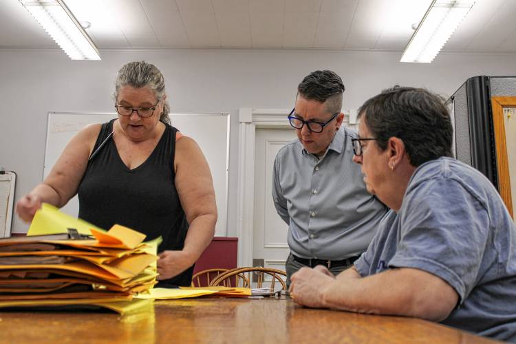 From left, City Clerk Kathy Scott and Assistant City Clerk Quinn Jaquins oversee poll worker Cathy Marcum as she works to tabulate 10 mail-in ballots at Greenfield City Hall on Tuesday morning.