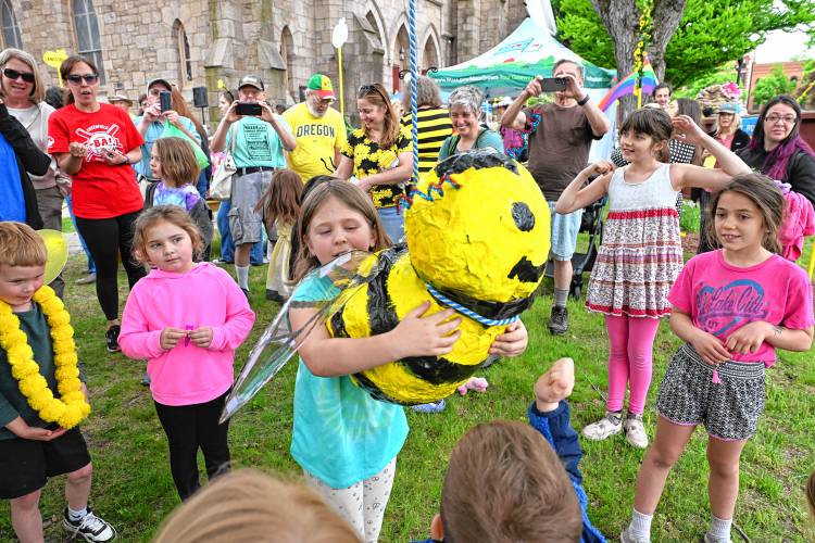 A child hugs the bee pinata before it was destroyed at the 14th Annual Bee Fest in Greenfield Saturday. 